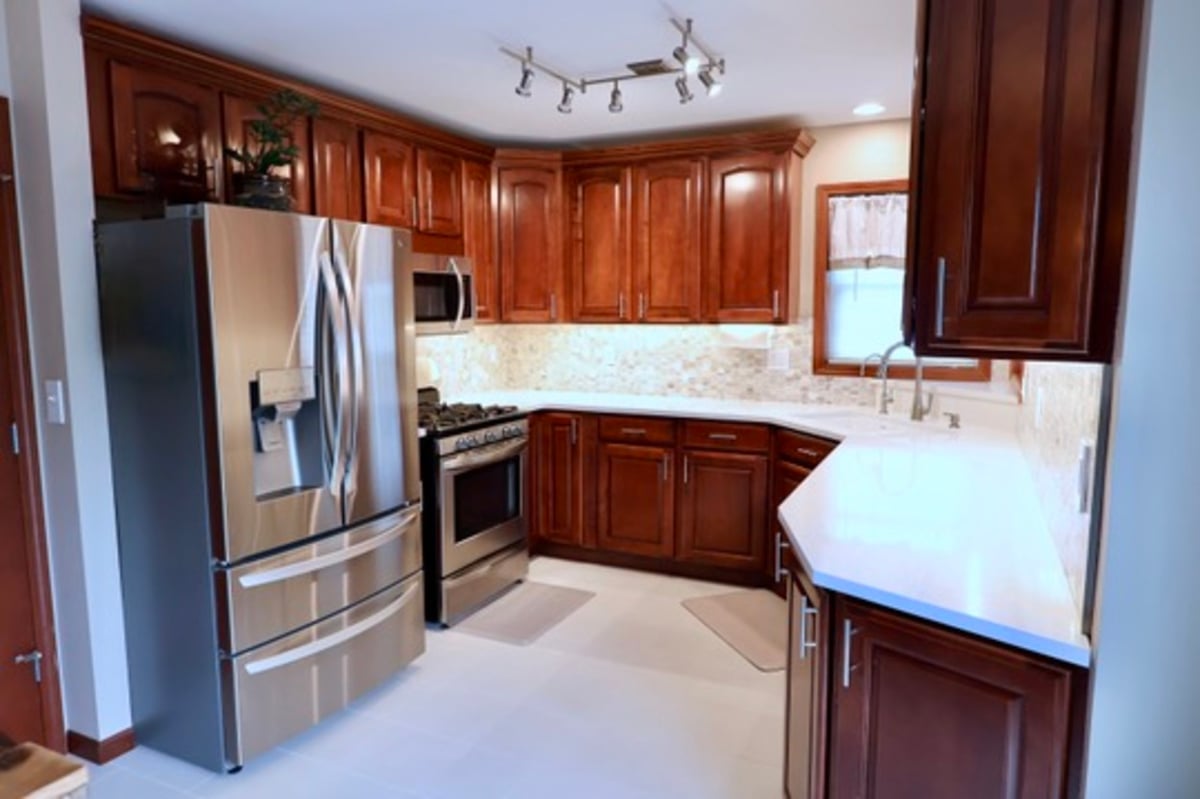 Kitchen update in Lowell featuring stainless steel fridge and cherry wood cabinets