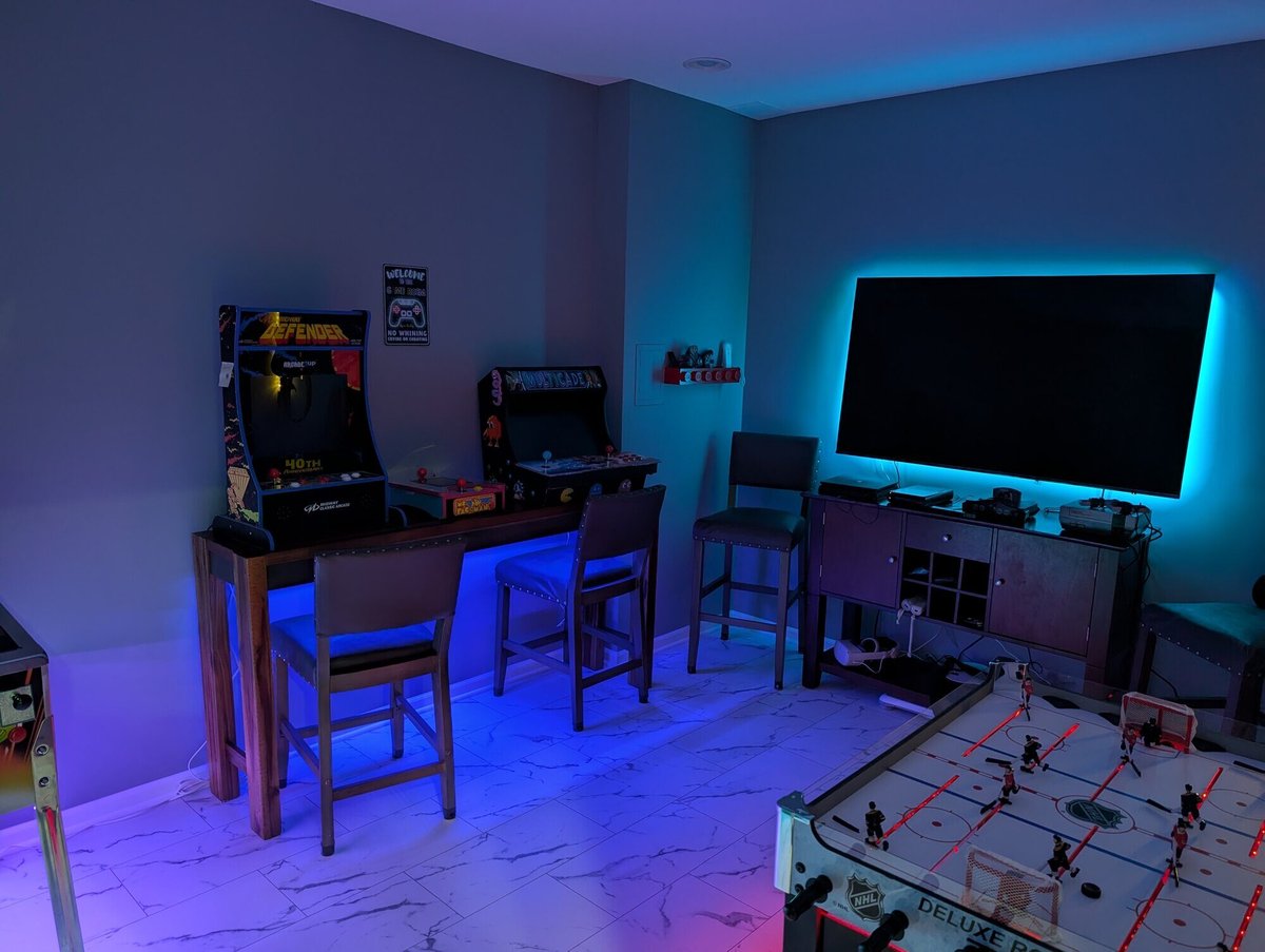 Basement game room featuring retro arcade games, colorful lighting, and a TV, remodeled by Clear Contractors in Northwest Indiana