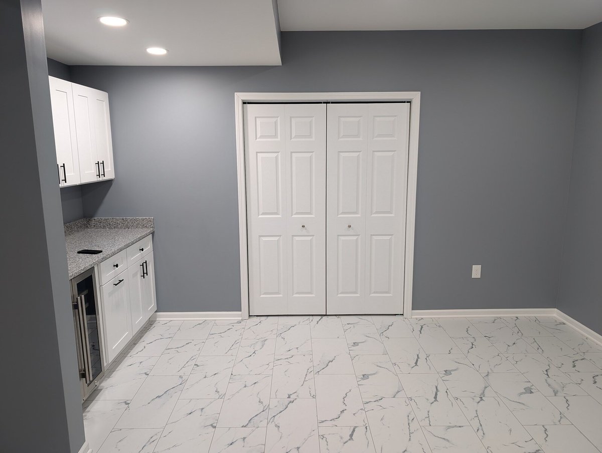 Basement kitchenette with white cabinets, granite countertops, and double doors, remodeled by Clear Contractors in Northwest Indiana