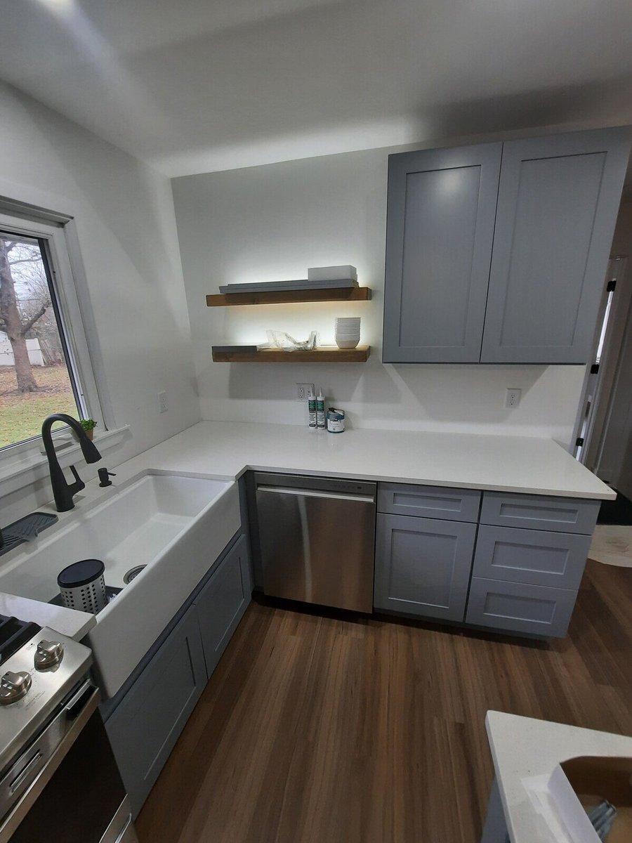 Remodeled kitchen corner with floating wooden shelves, a farmhouse sink, and gray cabinetry by Clear Contractors in Northwest Indiana