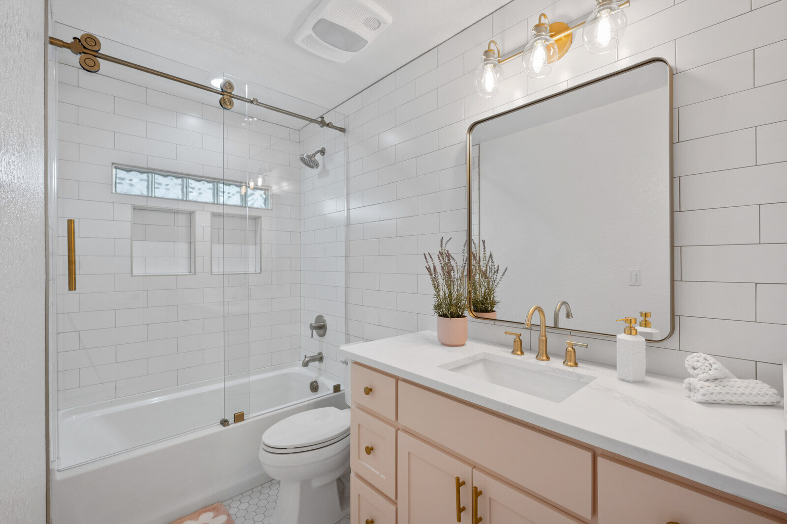 Bright bathroom with subway tiles and a gold-accented mirror by Clear Contractors in Northwest Indiana