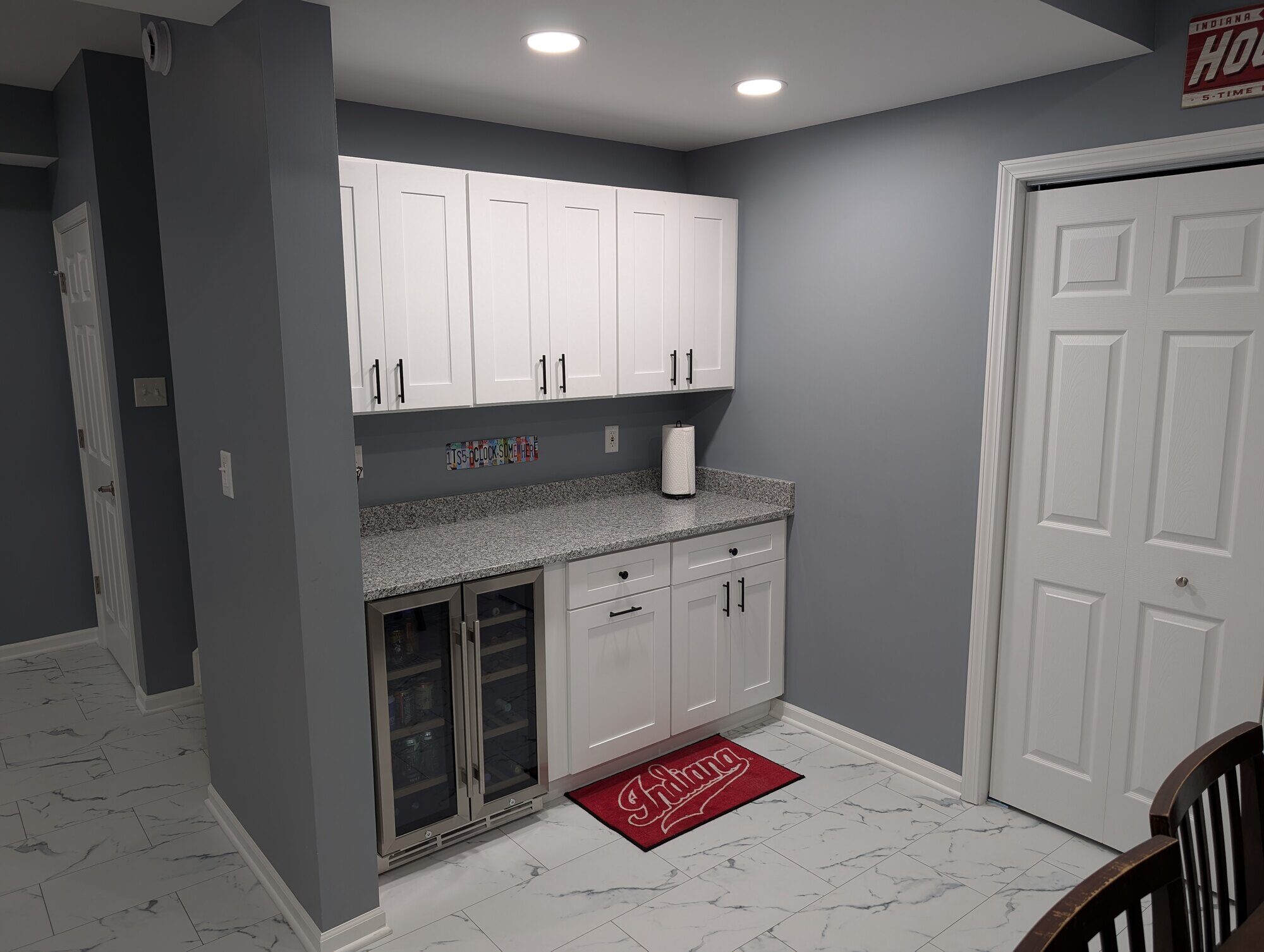 Kitchenette with granite countertops and white cabinets in a basement remodel by Clear Contractors in Northwest Indiana